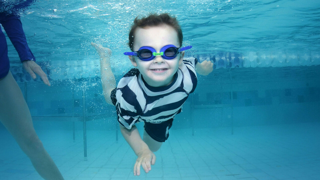 Kid swimming underwater with googles.