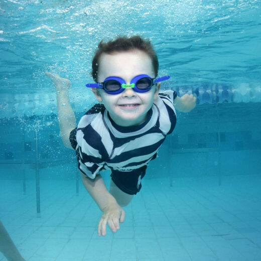Kid swimming underwater with googles.