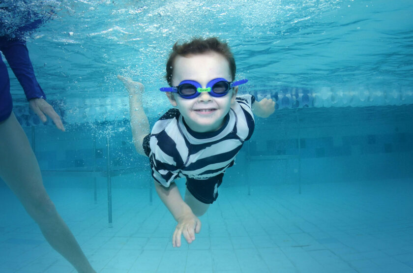 Kid swimming underwater with googles.